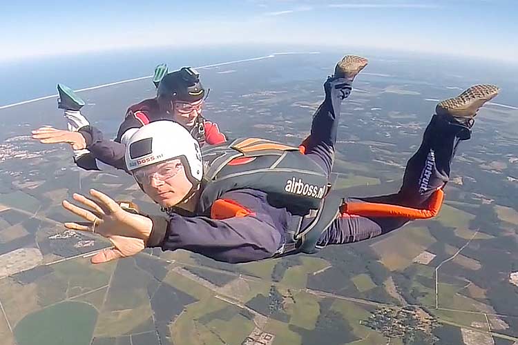 AFF-opleiding bij Airboss – eerste sprong met instructeurs Twee skydivers in vrije val tijdens de AFF-opleiding van Airboss, met uitzicht op de Atlantische kust