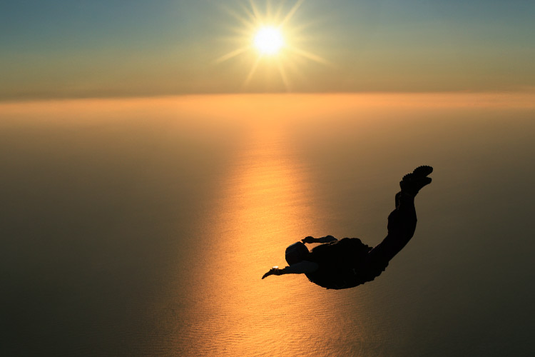 Skydiver in vrije val bij zonsondergang boven zee, symbool voor mentale focus en overgave
