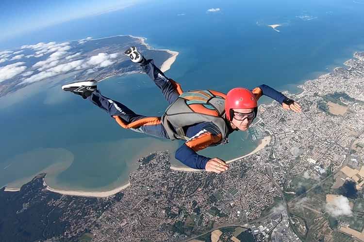 Skydiver boven de kust van Royan in stabiele buikpositie met parachuteuitrusting