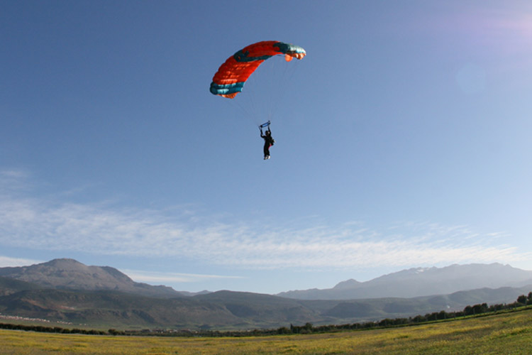 Skydiver in Morocco with the Atlas Mountains in the background, landing on the grass field during Skydive Morocco 2026.