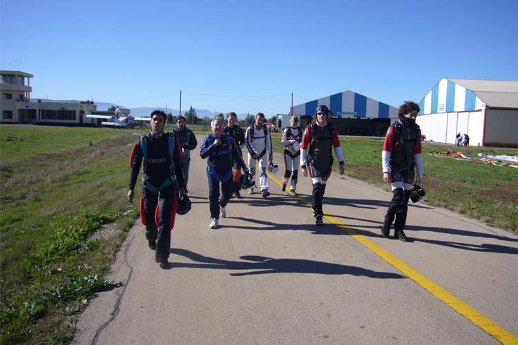 Skydivers lopen naar het vliegtuig in Beni Mellal Groep skydivers in pak loopt over de taxiway richting het vliegtuig