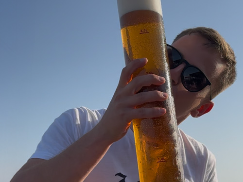 Skydiveweek Royan – ontspanning aan zee na het springen Deelnemer geniet van een groot glas bier op het terras aan zee na een skydive-dag in Royan.