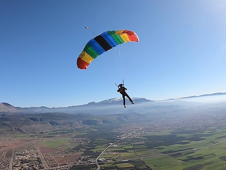 Kleurrijke canopy boven Beni Mellal Skydiver onder een kleurrijke parachute boven de vallei bij Beni Mellal in Marokko, met het Atlasgebergte op de achtergrond.
