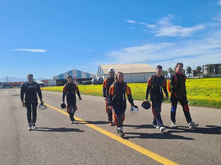 On the way to the next load Group of skydivers in gear walking along the runway at the dropzone in Morocco, ready for the next jump.